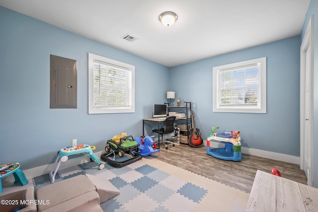 home office featuring electric panel, wood finished floors, and baseboards