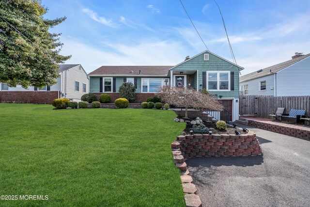 view of front of property with driveway, a front yard, fence, and a garage