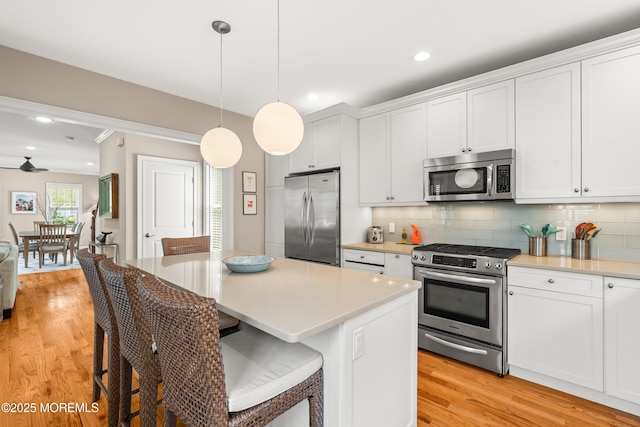 91 Cookman Ave, Ocean Grove, NJ 07756 - kitchen featuring stainless steel appliances, light wood finished floors, decorative backsplash, a breakfast bar, and white cabinetry
