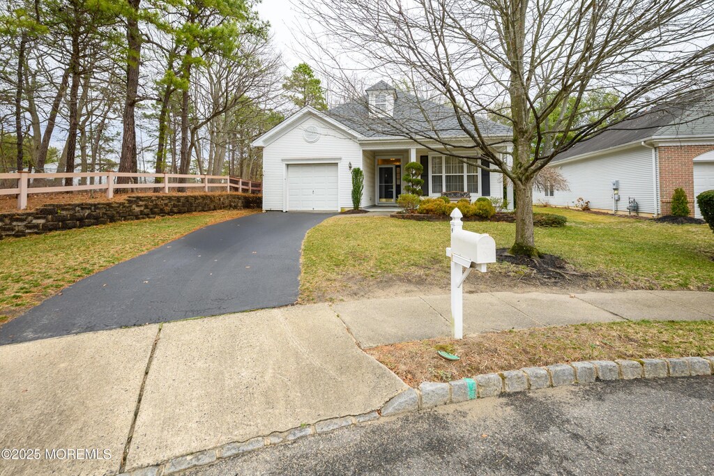 view of front facade with a front lawn, an attached garage, fence, and driveway
