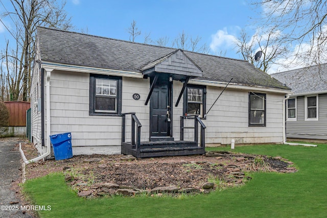 bungalow-style home with a front lawn, fence, and roof with shingles