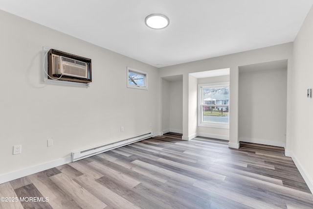 spare room with a baseboard heating unit, baseboards, and wood finished floors