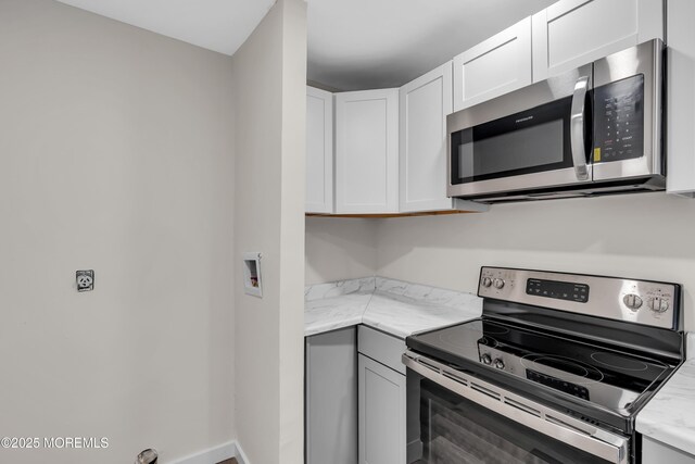 kitchen featuring white cabinetry, stainless steel appliances, and light stone countertops