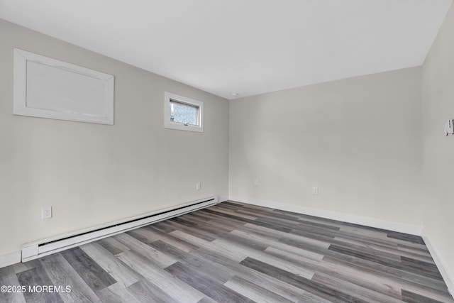 spare room featuring wood finished floors, baseboards, and baseboard heating