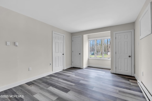 unfurnished bedroom featuring a baseboard radiator, baseboards, and wood finished floors