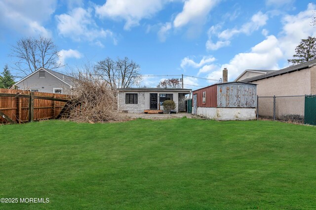 rear view of property with a lawn, an outdoor structure, and a fenced backyard