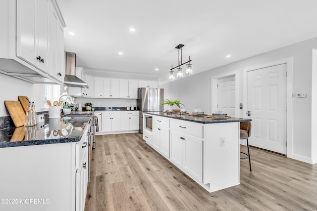 kitchen featuring wall chimney exhaust hood, light wood-type flooring, white cabinets, recessed lighting, and a kitchen breakfast bar