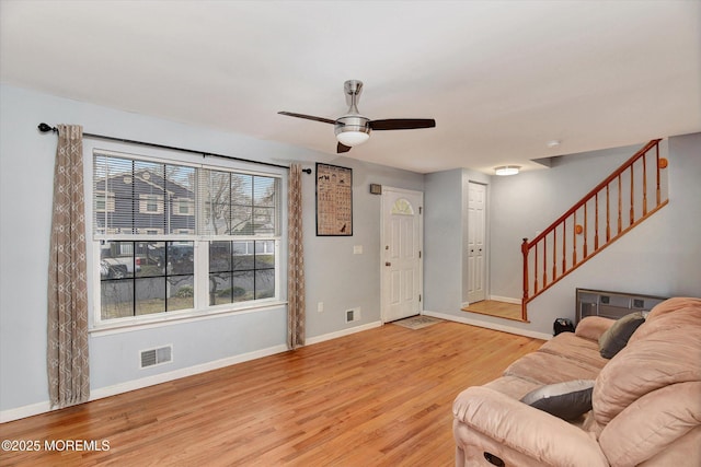 living room with visible vents, baseboards, stairs, wood finished floors, and a ceiling fan