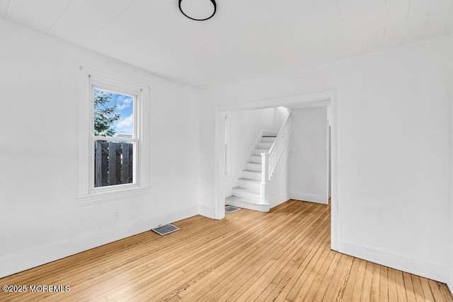 empty room featuring baseboards, light wood-style floors, and visible vents
