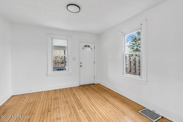 entryway with baseboards, a wealth of natural light, light wood finished floors, and visible vents