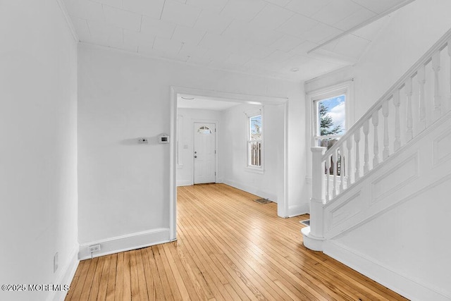 entryway featuring light wood finished floors, visible vents, baseboards, and stairs