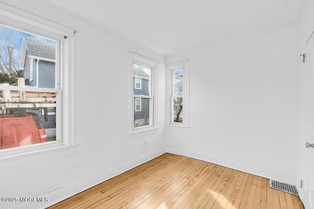 spare room featuring visible vents, light wood-style flooring, and baseboards