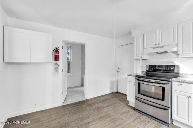kitchen featuring under cabinet range hood, stainless steel range with electric stovetop, baseboards, and white cabinets