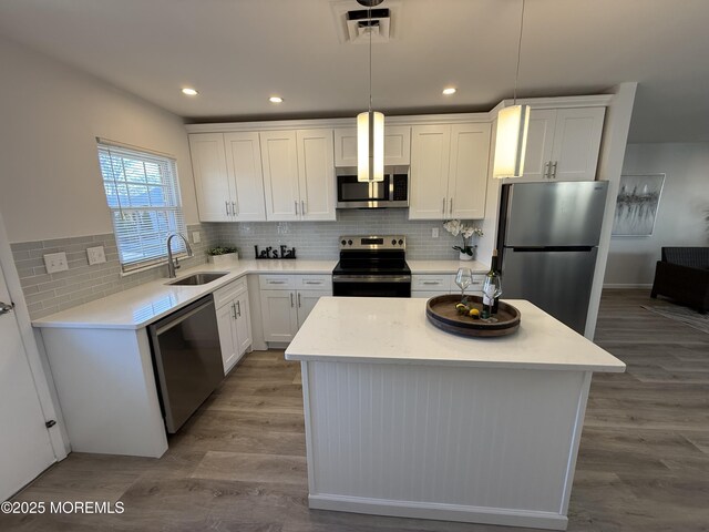 kitchen with a center island, wood finished floors, appliances with stainless steel finishes, and a sink