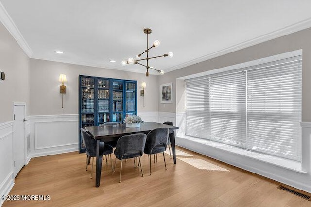 dining room featuring ornamental molding, visible vents, a notable chandelier, and light wood finished floors