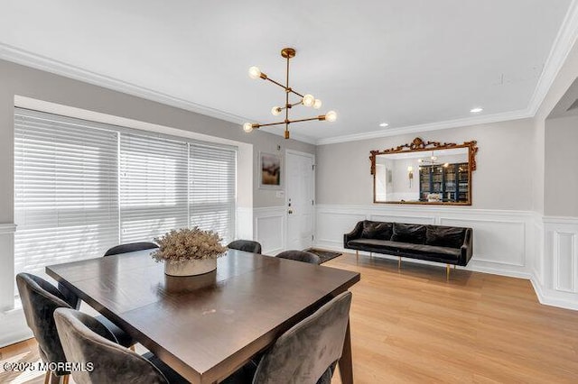 dining space with an inviting chandelier, wainscoting, crown molding, and light wood-type flooring