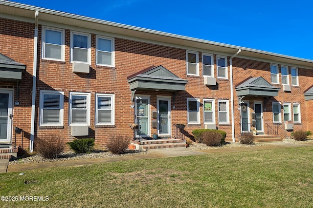 townhome / multi-family property with a front yard and brick siding