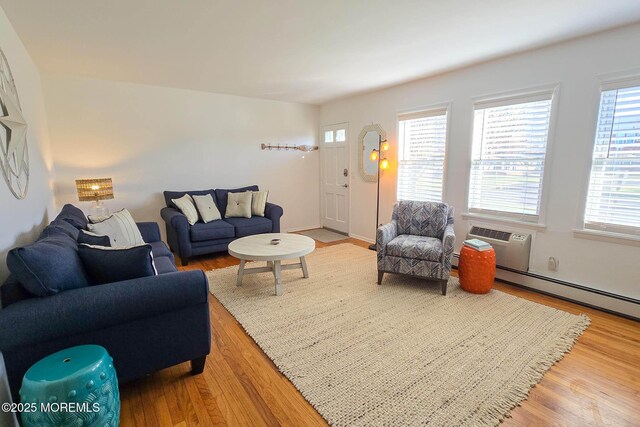 living area featuring a wall unit AC, wood finished floors, and a baseboard radiator