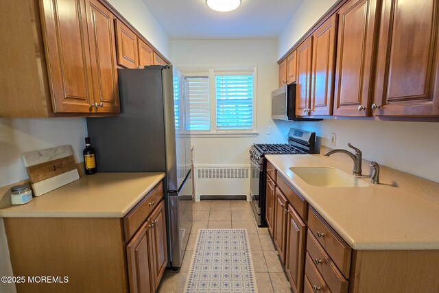 kitchen with appliances with stainless steel finishes, light countertops, radiator heating unit, and a sink