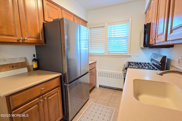 kitchen featuring brown cabinetry, stainless steel appliances, radiator heating unit, and a sink