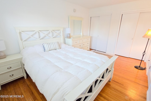 bedroom featuring light wood-style flooring and two closets