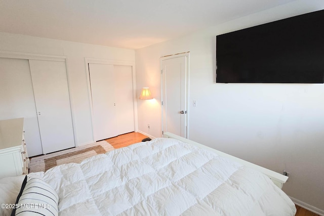 bedroom with two closets and light wood finished floors