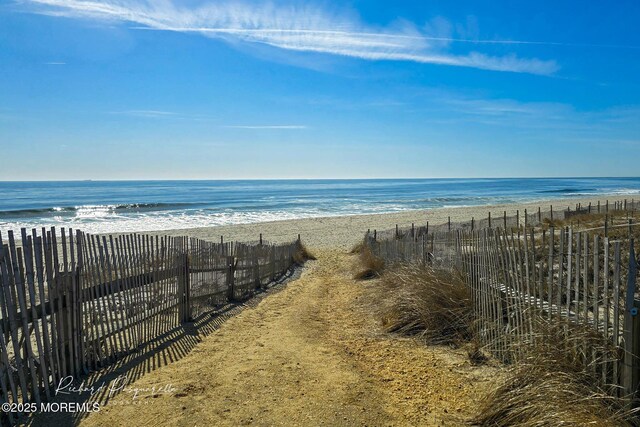 property view of water with fence and a beach view