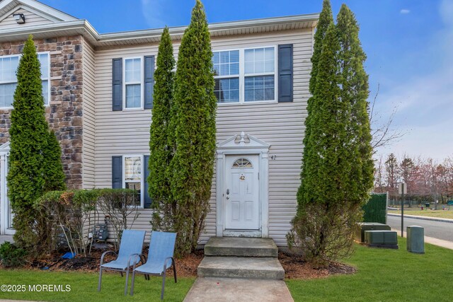 townhome / multi-family property featuring cooling unit and a front lawn