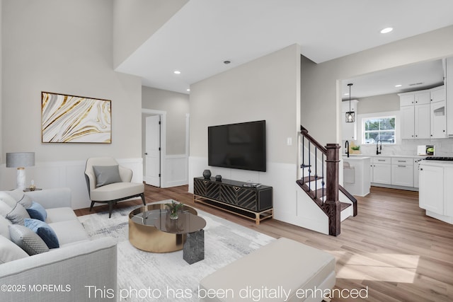 living area with light wood finished floors, stairway, wainscoting, and recessed lighting