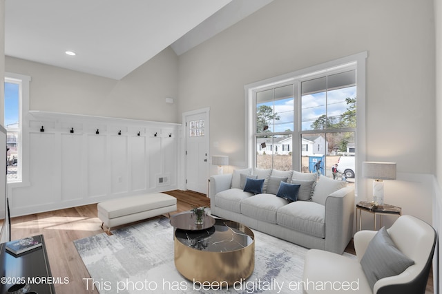 living room featuring wood finished floors, plenty of natural light, and a towering ceiling