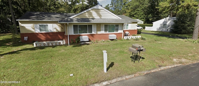 bungalow featuring a front yard and brick siding