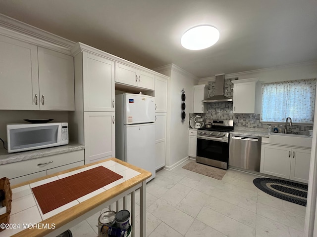 kitchen featuring wall chimney range hood, light countertops, appliances with stainless steel finishes, marble finish floor, and a sink