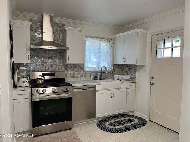 kitchen with ornamental molding, a sink, appliances with stainless steel finishes, wall chimney exhaust hood, and light countertops