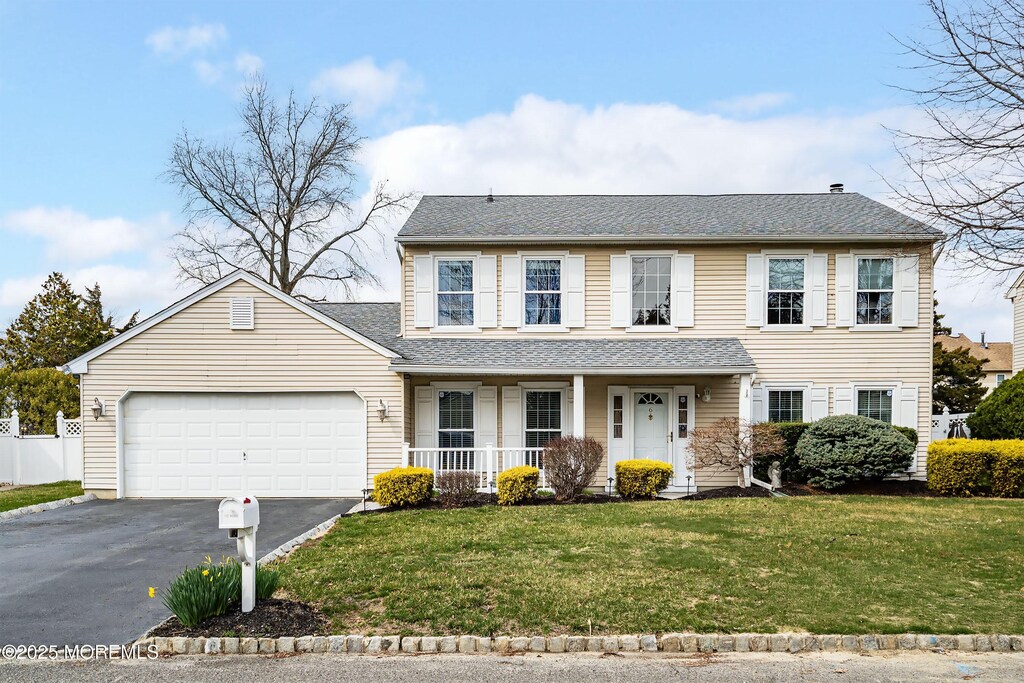 view of front facade with a front lawn, aphalt driveway, a porch, roof with shingles, and a garage