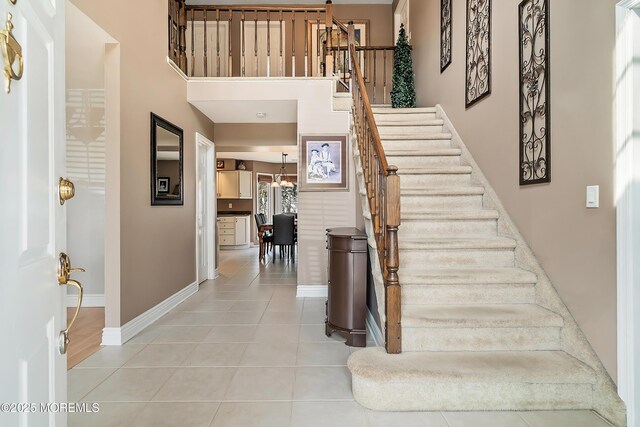 tiled foyer with baseboards, a towering ceiling, and stairs
