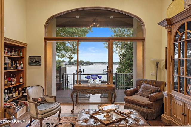 living area with a towering ceiling, a water view, and wood finished floors