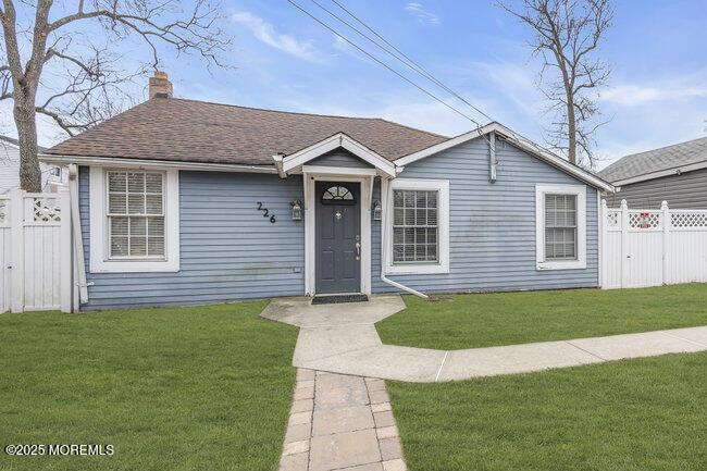 ranch-style house with a chimney, fence, a front lawn, and roof with shingles