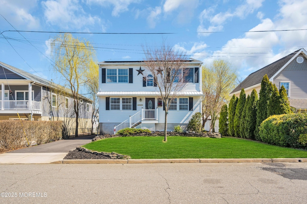 136 Oak Ave, Island Heights, NJ 08732 - view of front of home featuring driveway, roof mounted solar panels, and a front yard