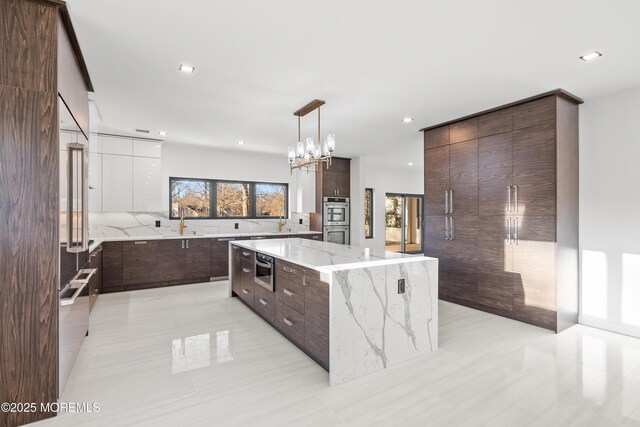 kitchen with dark brown cabinets, decorative light fixtures, a large island, and modern cabinets