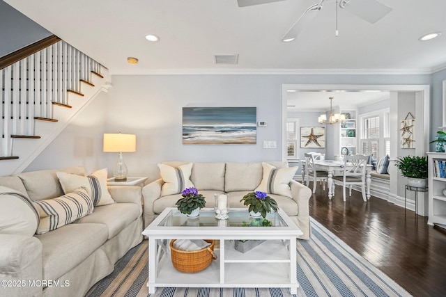 living area with stairs, wood finished floors, ceiling fan with notable chandelier, ornamental molding, and visible vents
