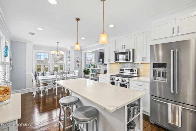 kitchen featuring white cabinets, stainless steel appliances, a center island, dark wood-type flooring, and ornamental molding