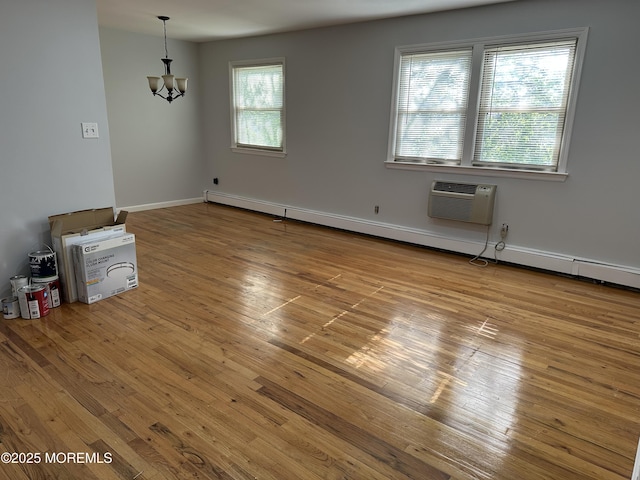 unfurnished room with a chandelier, hardwood / wood-style flooring, and baseboards