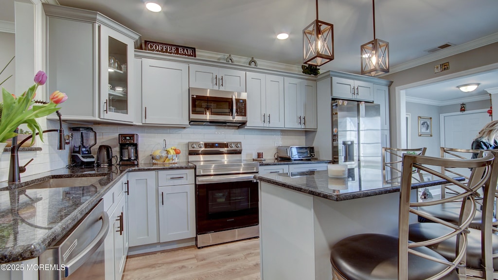 75 William And Mary Sq Unit B, Freehold, NJ 07728 - kitchen with crown molding, a kitchen bar, appliances with stainless steel finishes, light wood-type flooring, and visible vents