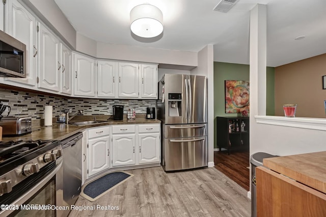 kitchen with white cabinetry, visible vents, light wood-type flooring, and stainless steel appliances