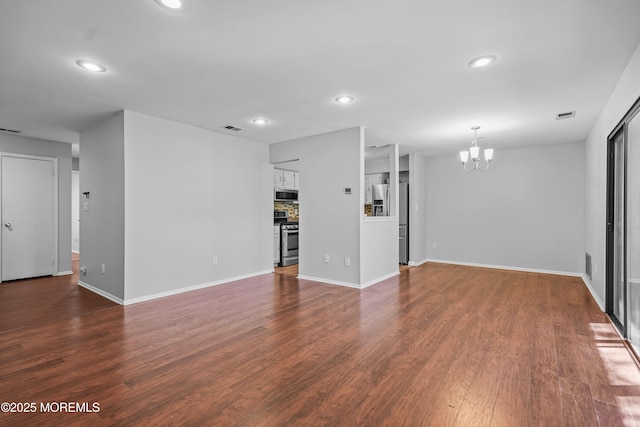 unfurnished living room with an inviting chandelier, dark wood finished floors, visible vents, and recessed lighting