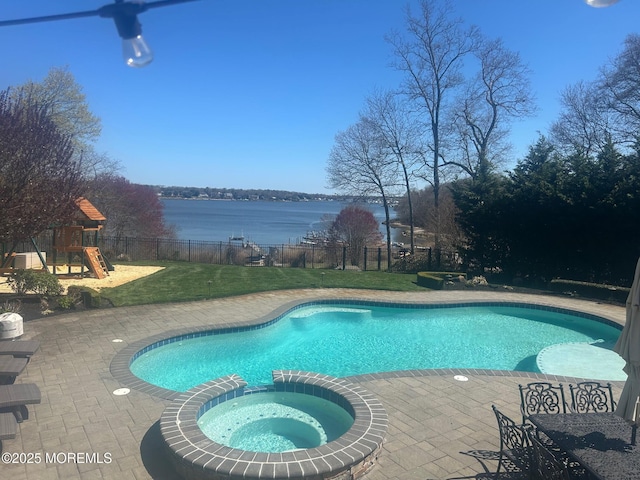 view of swimming pool featuring a lawn, fence, a pool with connected hot tub, and a patio area
