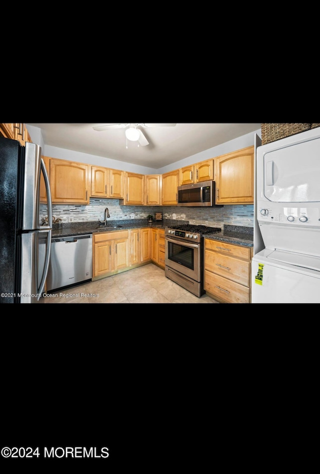 kitchen with stacked washer and dryer, appliances with stainless steel finishes, light brown cabinets, dark countertops, and decorative backsplash