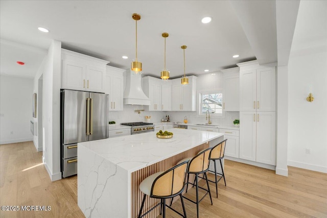 kitchen featuring custom range hood, white cabinets, light wood-style flooring, and high end refrigerator