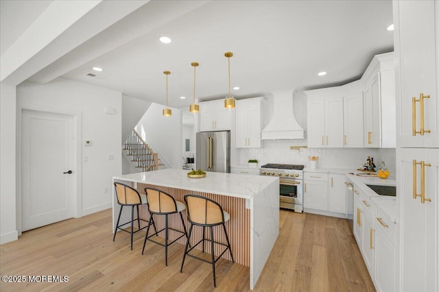 kitchen with a kitchen island, light wood-style floors, premium appliances, and premium range hood