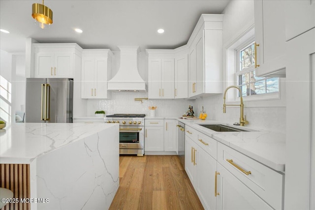 kitchen featuring decorative backsplash, custom exhaust hood, light wood finished floors, a sink, and premium appliances
